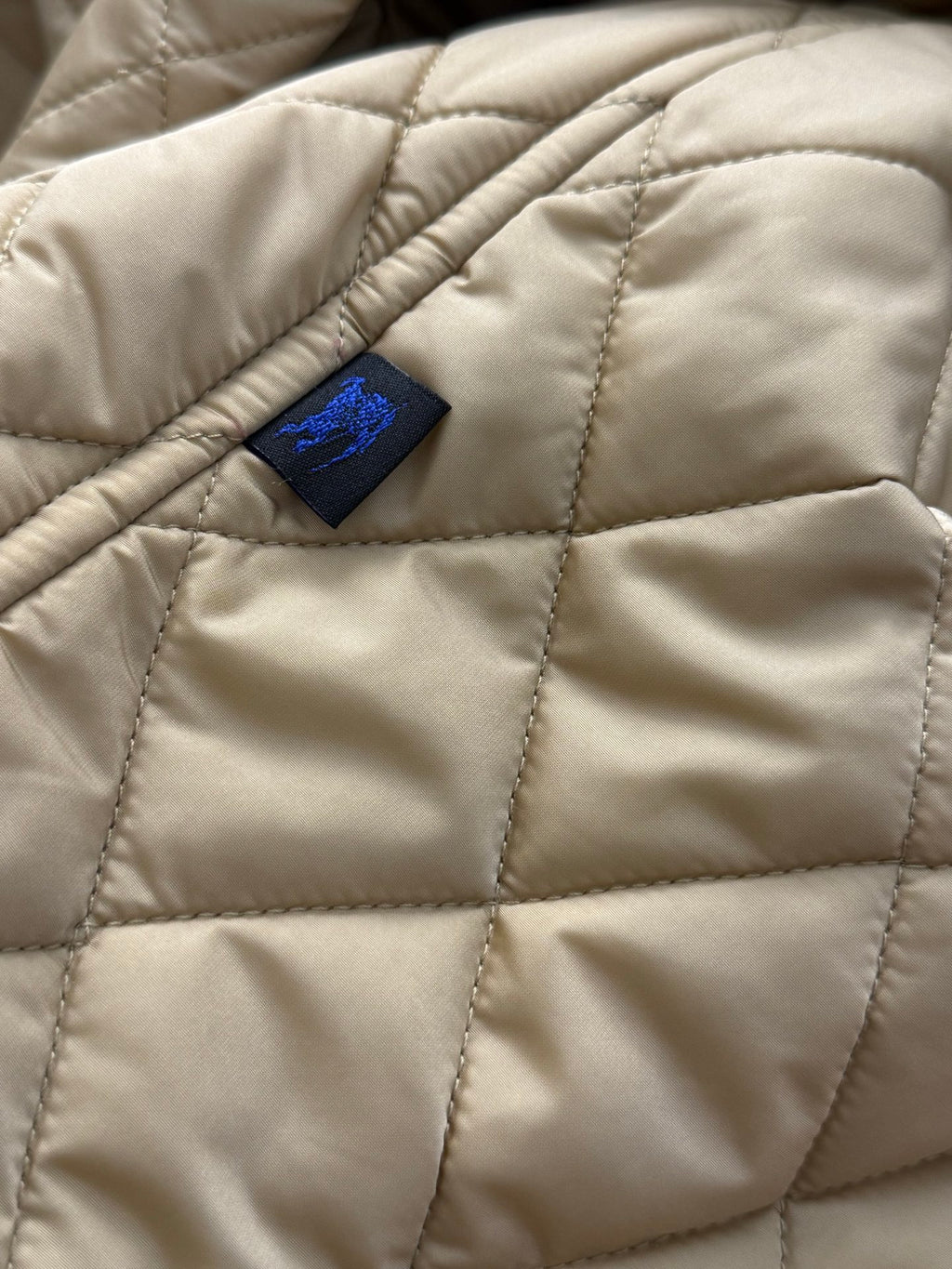 Quilted jacket interior panel with stitched diamond pattern and small blue care label