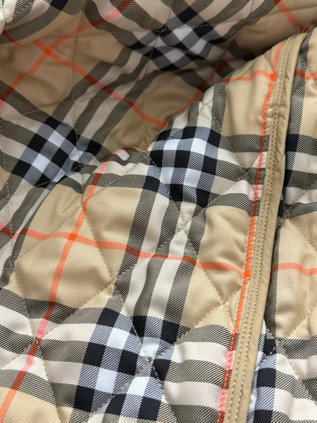 Plaid quilted lining with tan zipper seam and orange-red thread accents