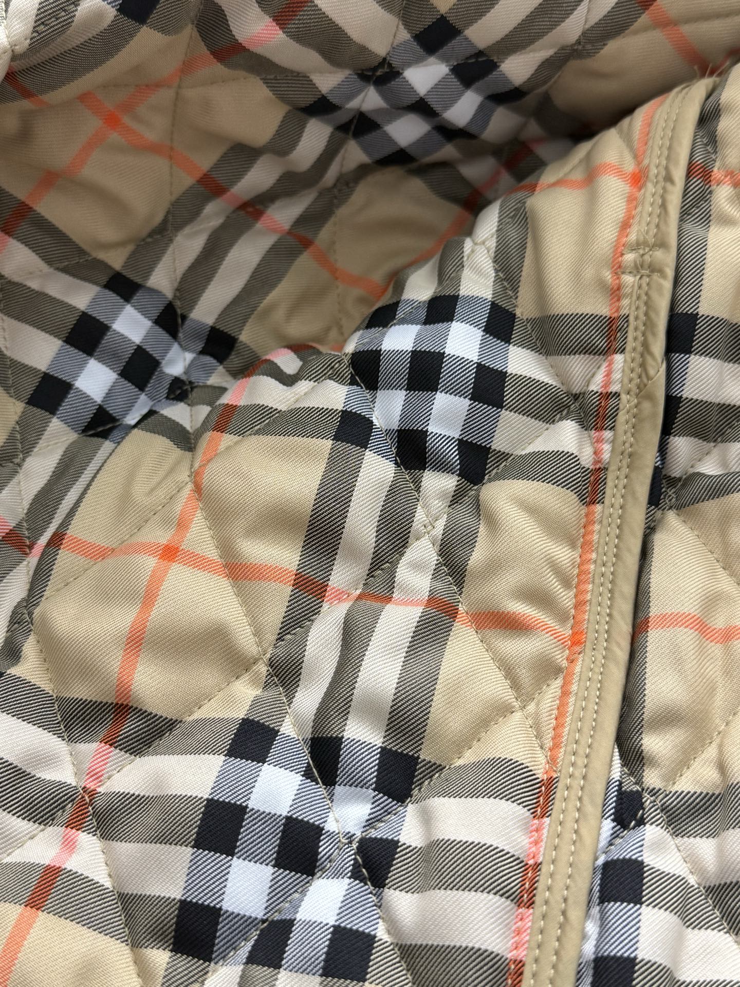 Plaid quilted lining with tan zipper seam and orange-red thread accents