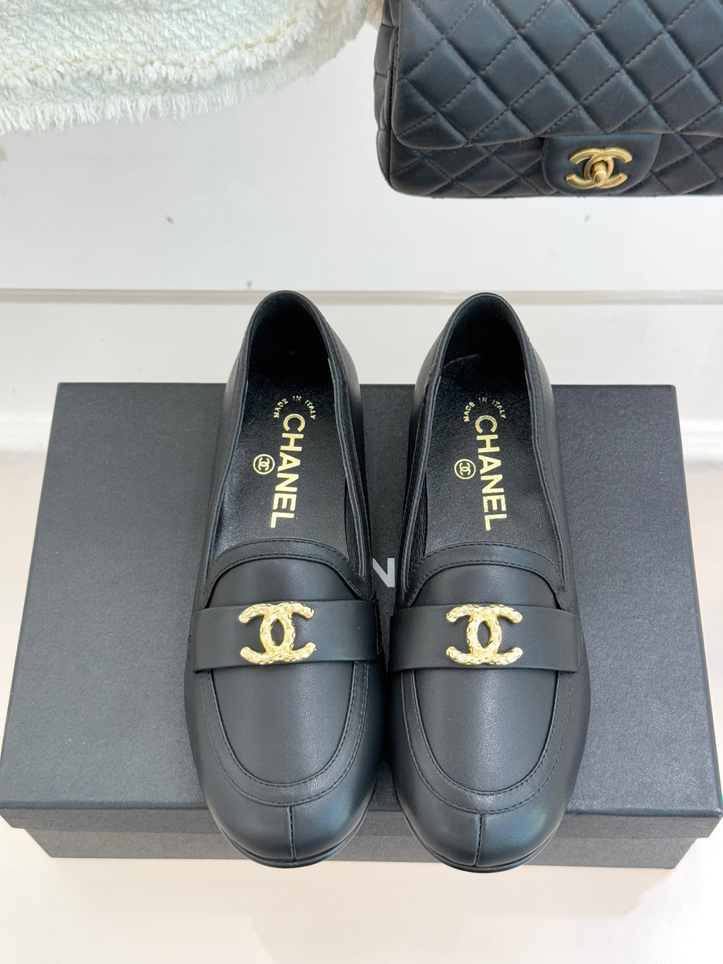 Chanel women’s black loafers with gold CC logo on strap, front view