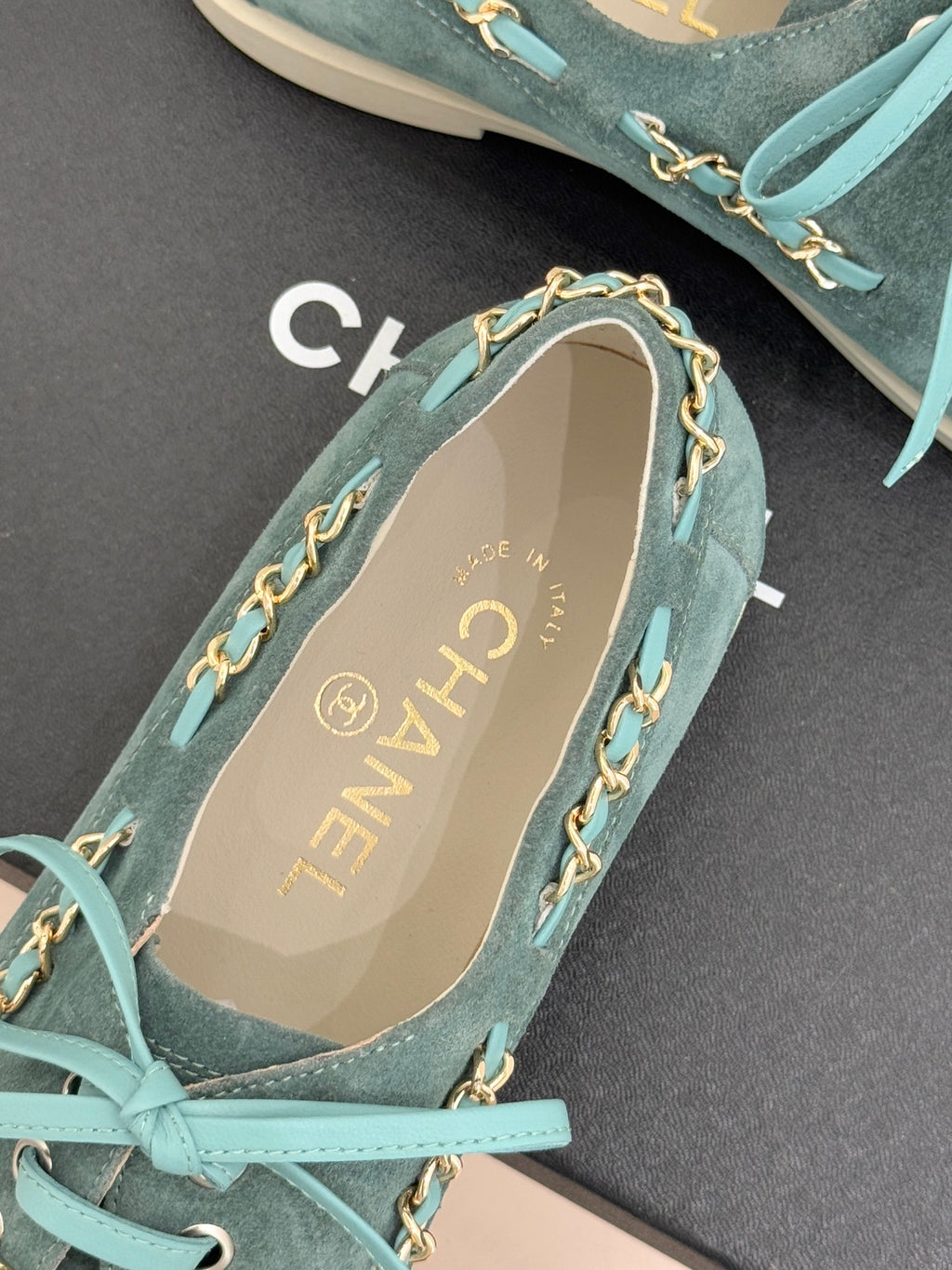 Chanel ladies blue suede sneaker close-up, gold chain trim on side and beige insole