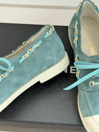 Chanel ladies blue suede sneakers close-up, gold chain trim and teal lace tie