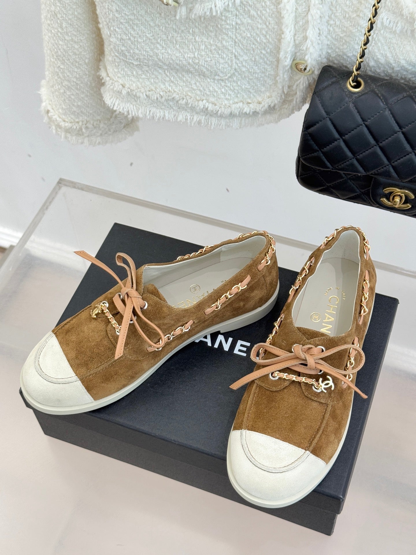 Pair of tan suede lace-up sneakers with white toe panels and pink lace-up ties