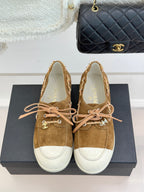 Tan suede lace-up sneakers with white toe panels and pink lace-up bow