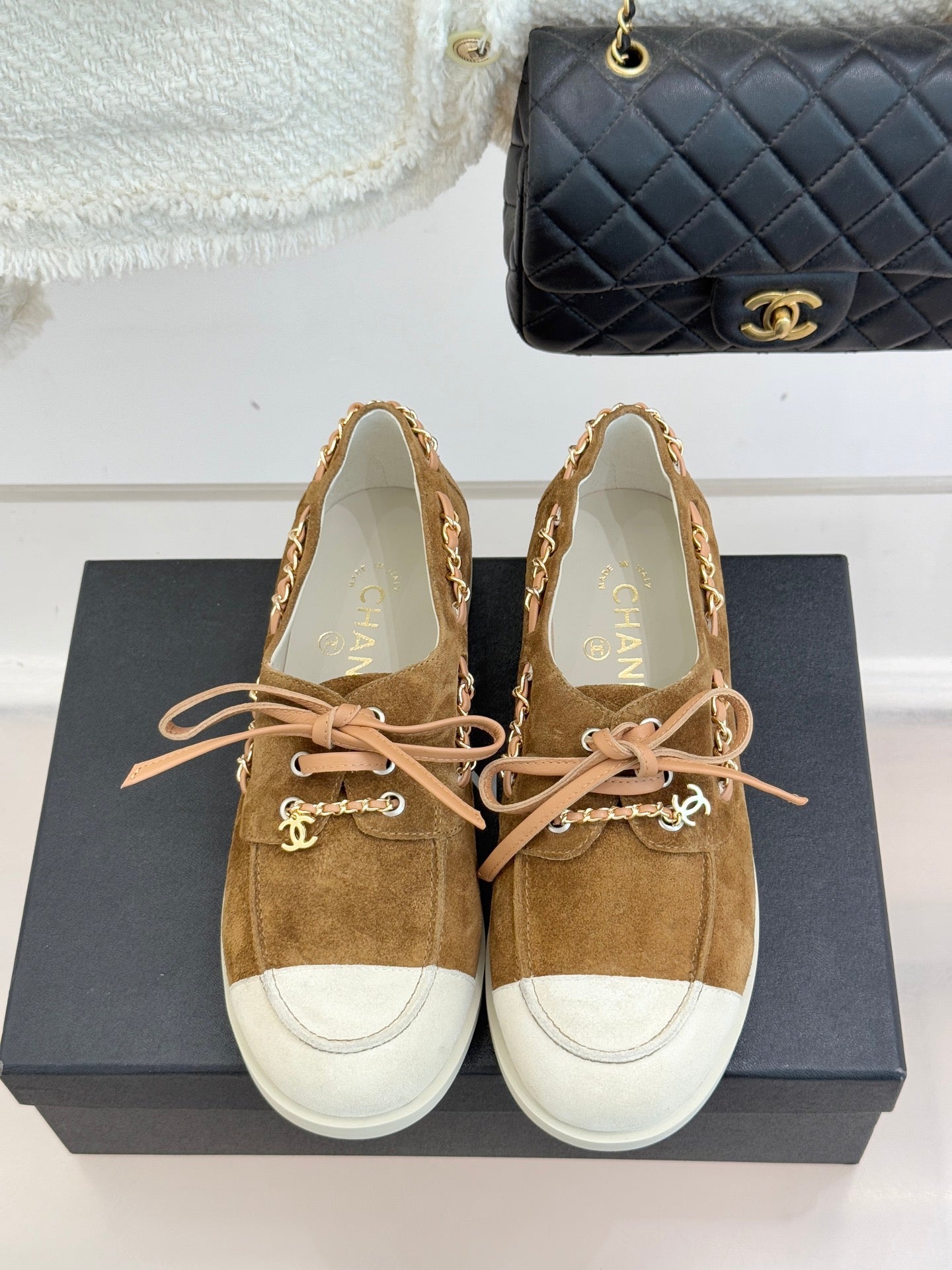 Tan suede lace-up sneakers with white toe panels and pink lace-up bow