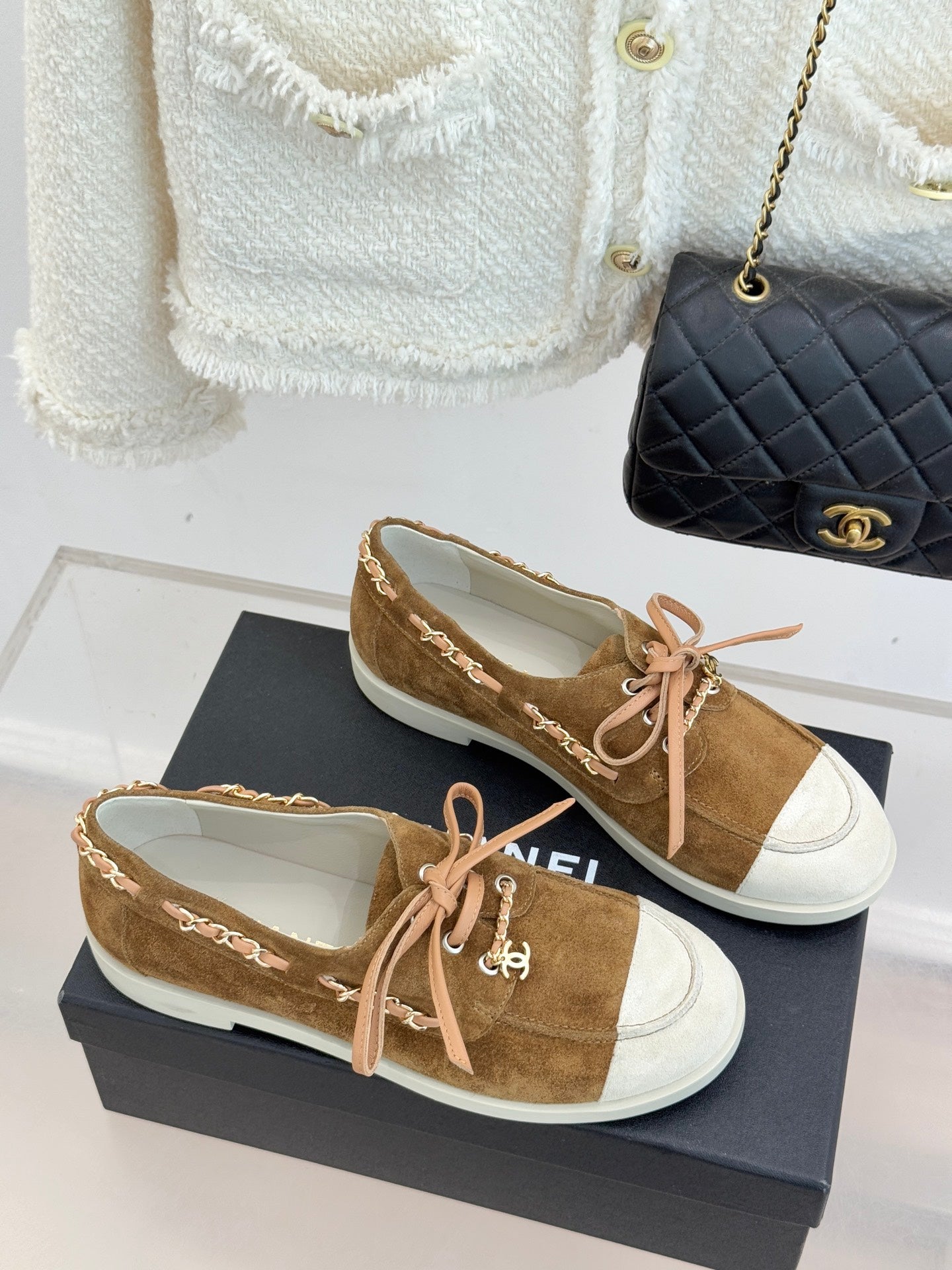 Tan suede lace-up sneakers with white toe panels, pink laces, and decorative chain detail
