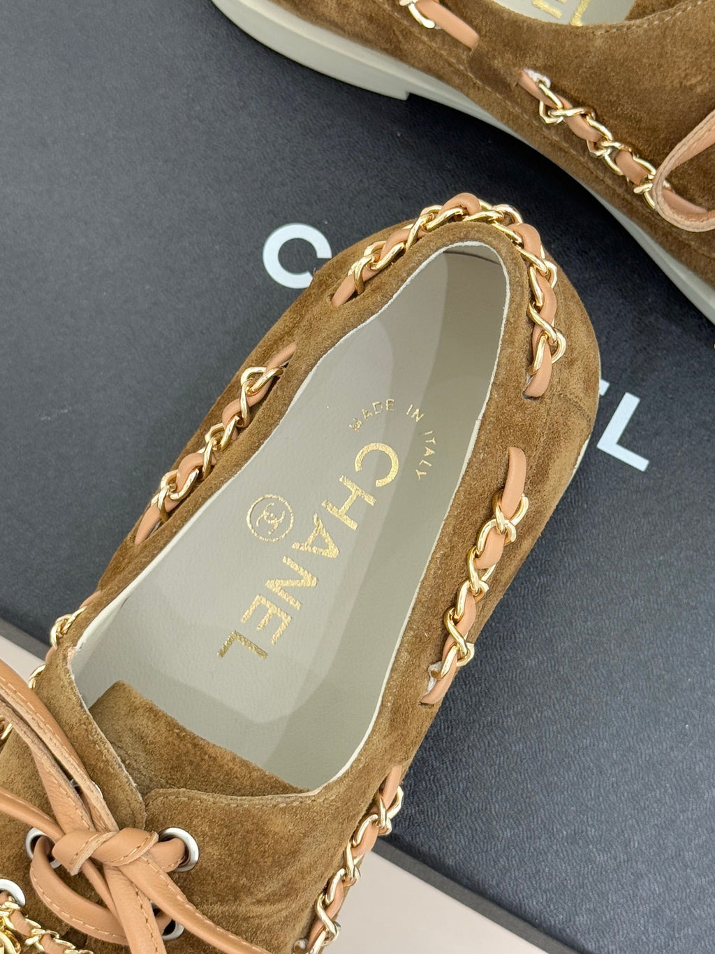 Tan suede sneaker with chain trim along the side and pale logo-lined insole
