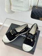 Black low-top sneakers with gold chain detail, lace-up front, and white toe panels