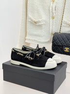 Black suede low-top sneakers with gold chain trim and white rubber sole