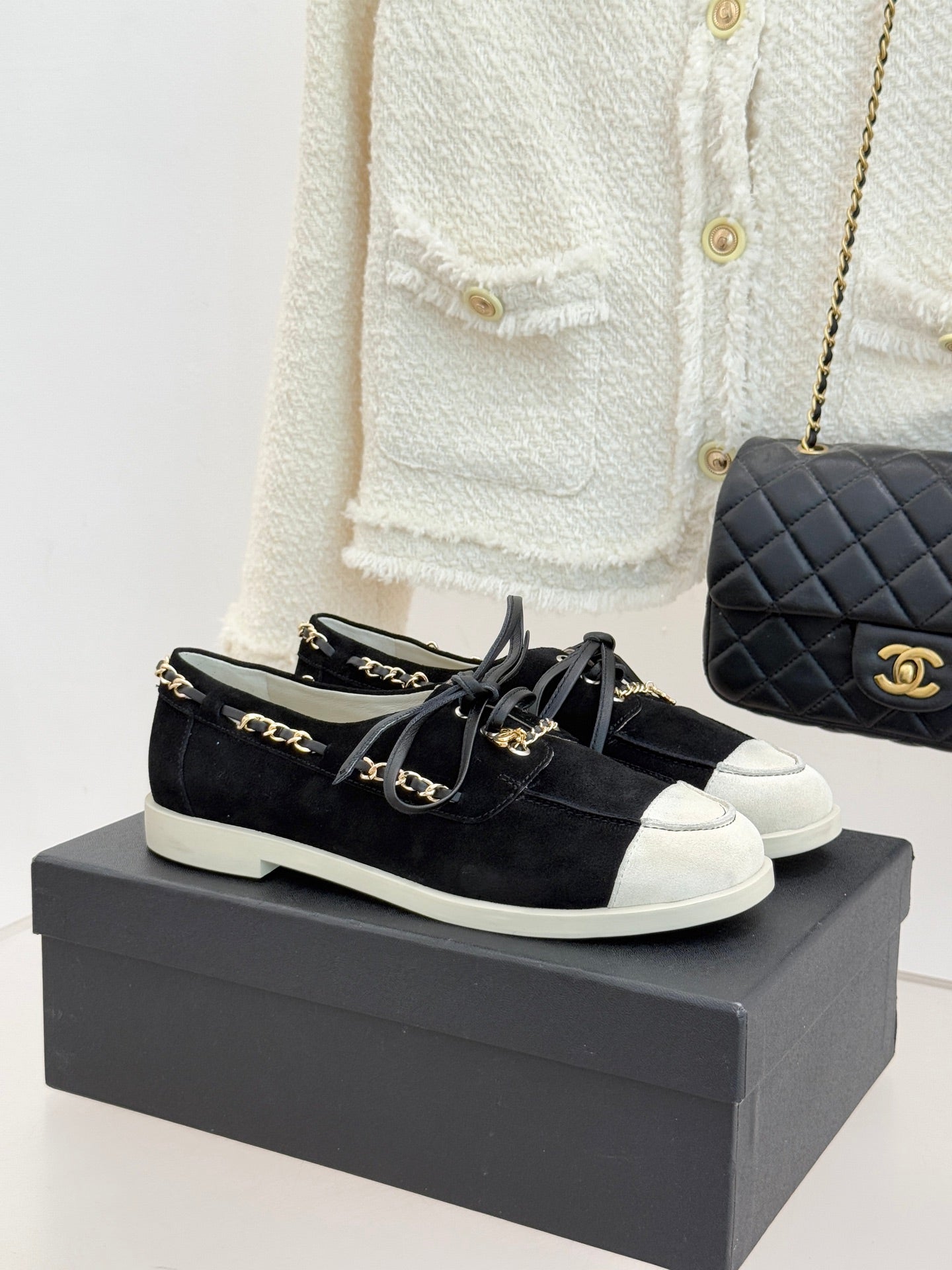 Black suede low-top sneakers with gold chain trim and white rubber sole