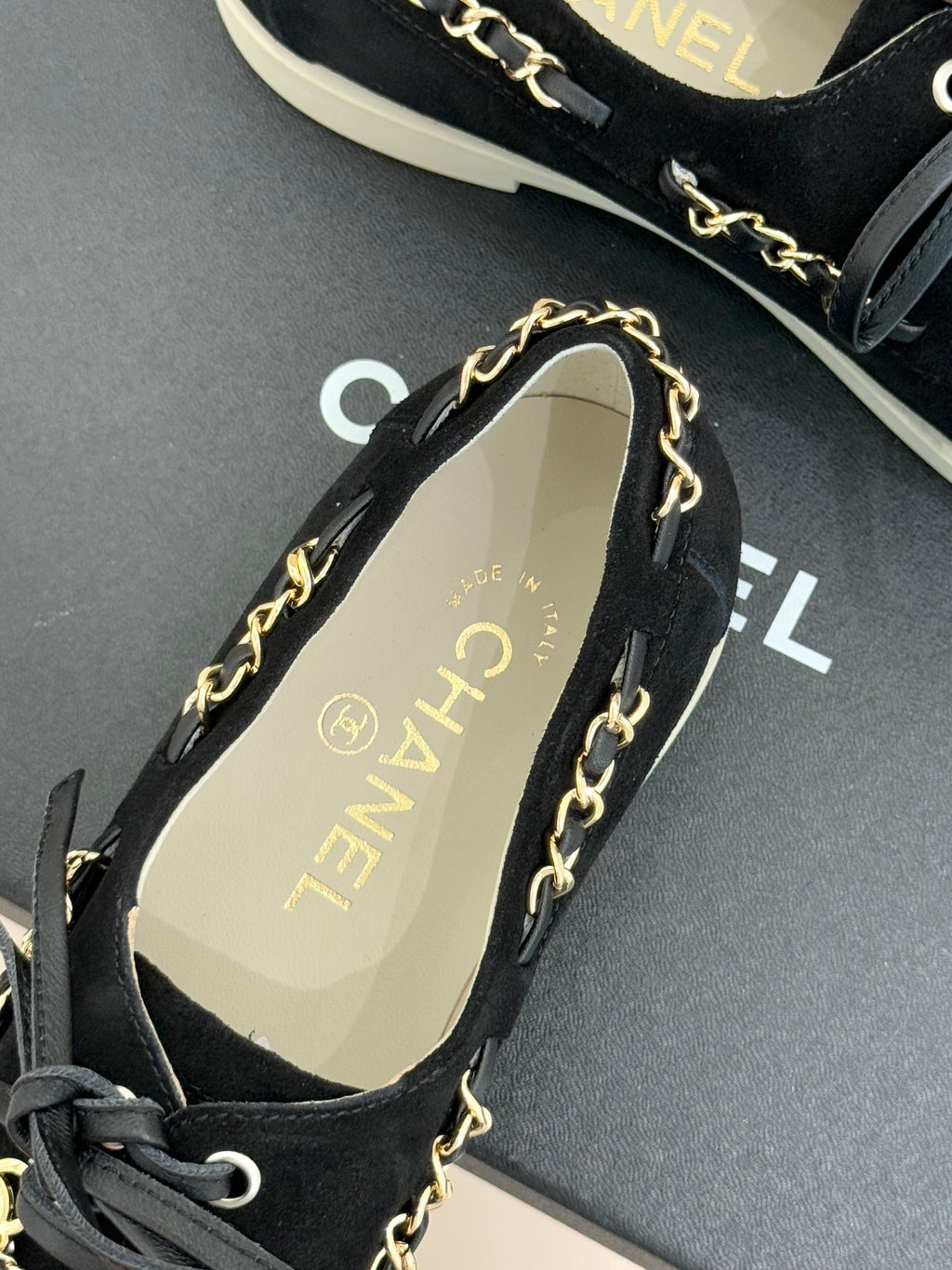Black suede low-top sneakers with gold chain trim and tan logo insole