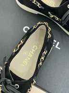 Black suede low-top sneakers with gold chain trim and tan logo insole