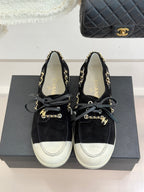 Black suede lace-up sneakers with gold chain trim and white toe and side panels