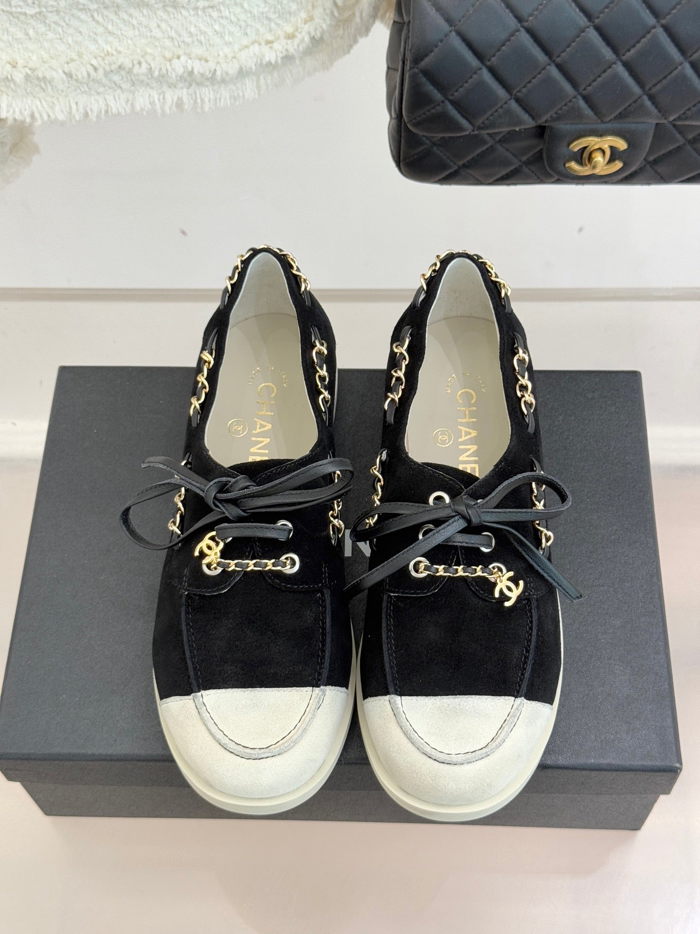 Black suede lace-up sneakers with gold chain trim and white toe and side panels