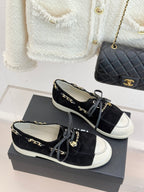 Pair of black suede low-top sneakers with gold chain trim and white side panels