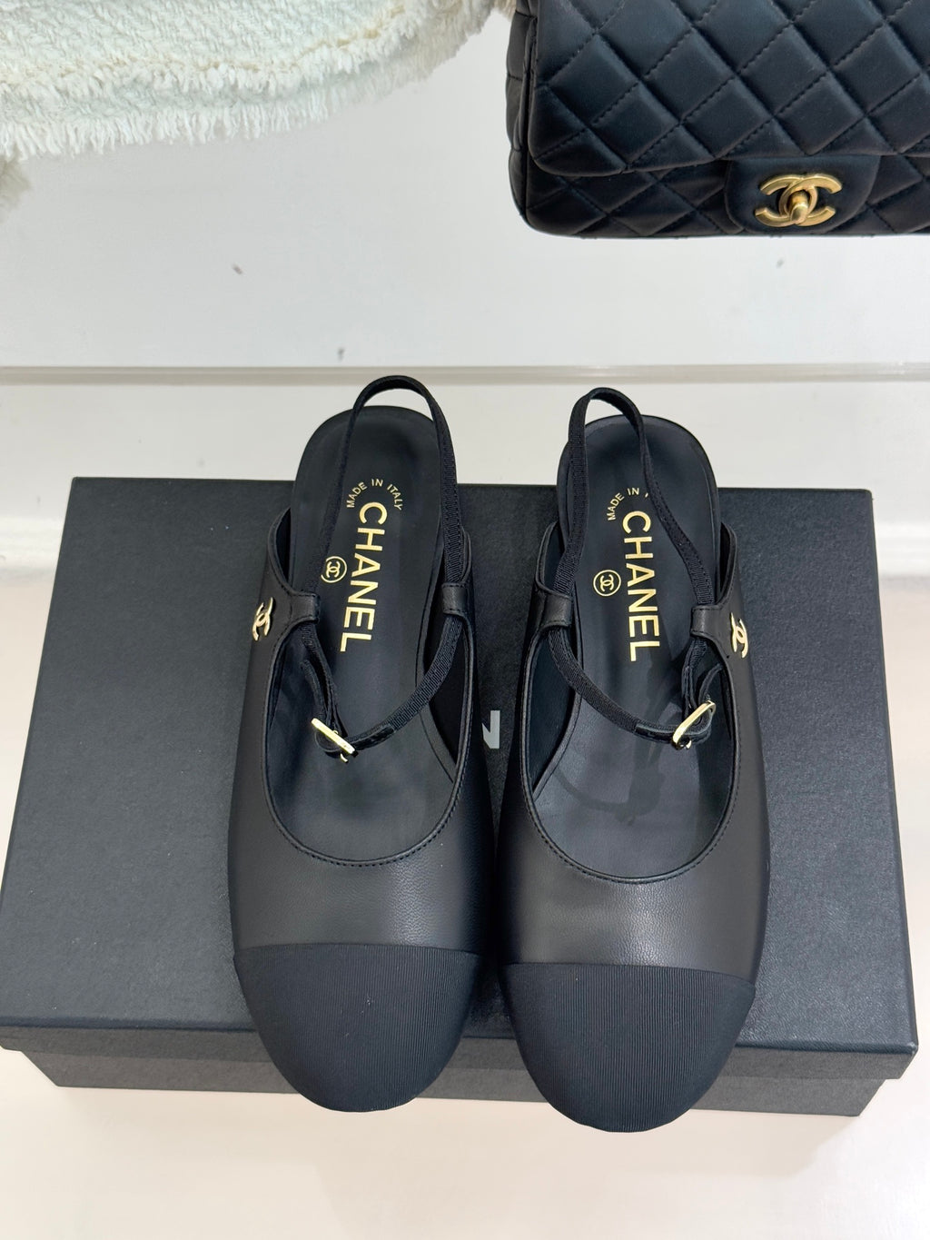 Dark CHANEL slingback flats with gold buckle and woven logo tab, front view