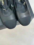 Dark slingback flats close-up showing platform sole and gold logo strap