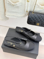 Pair of dark slingback flats with gold logo buckle, angled front view