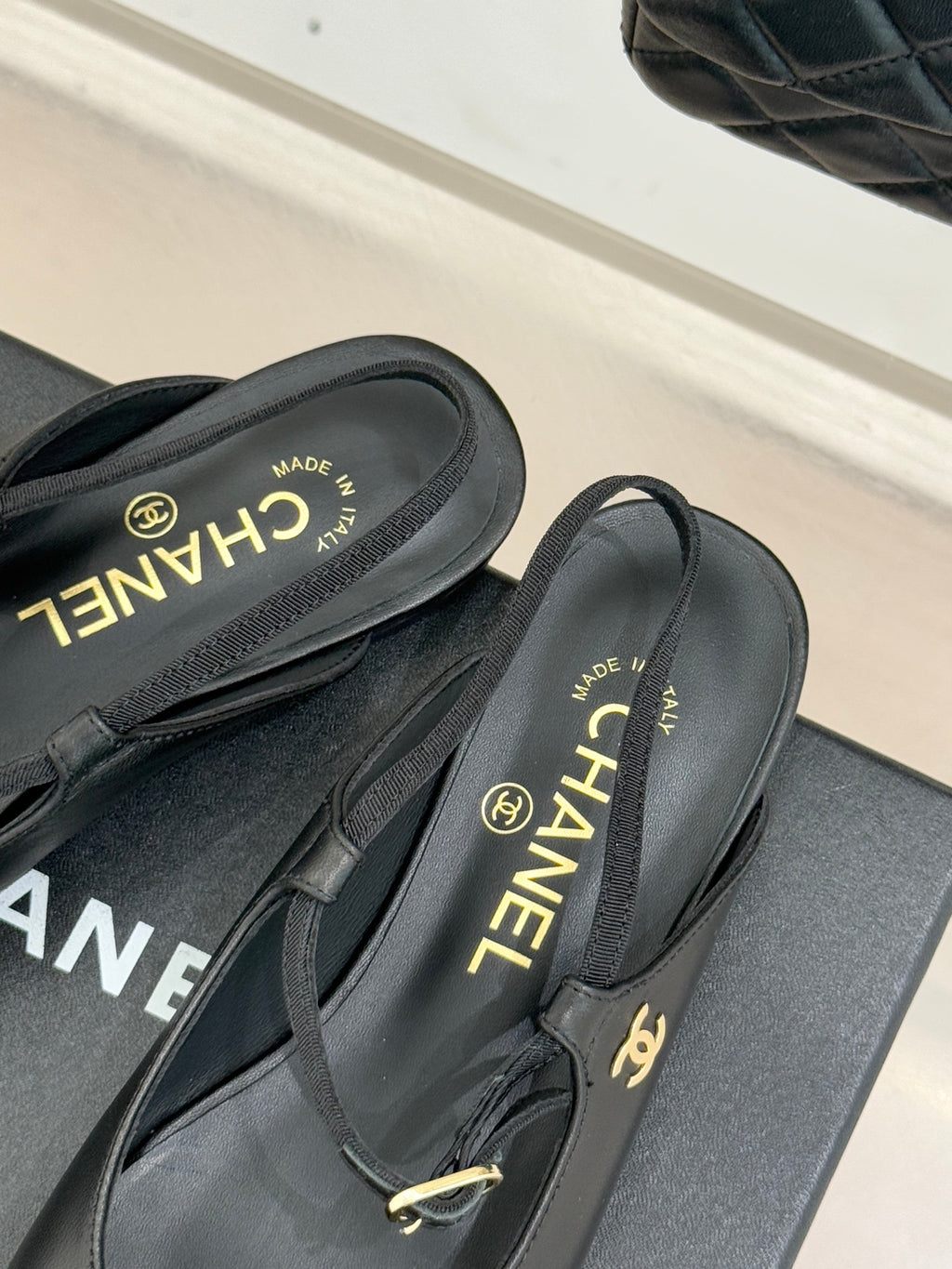Dark slingback flats with gold buckle and CHANEL text on the insole