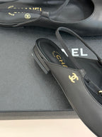 Dark slingback flats close-up, gold CHANEL logo on the strap