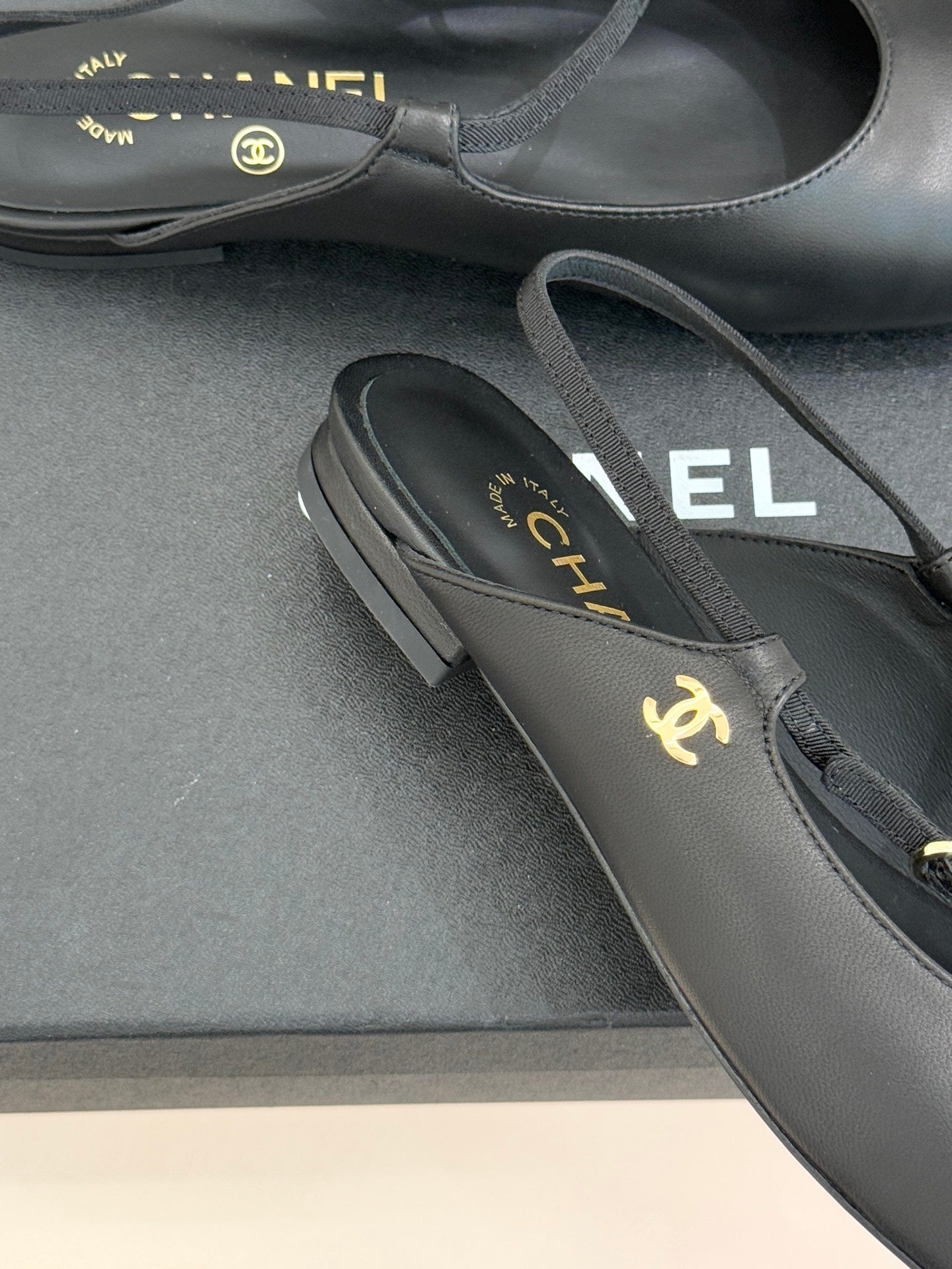 Dark slingback flats close-up, gold CHANEL logo on the strap