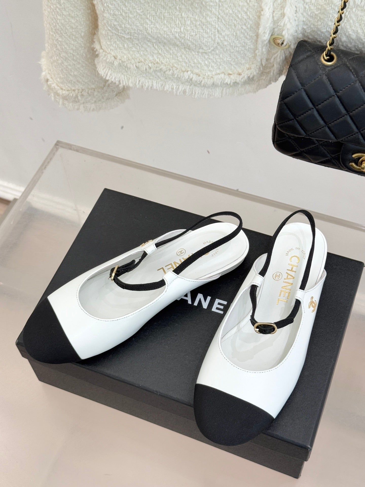 Pair of white and black Chanel flats with black toe caps and gold buckle