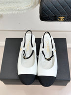 White Chanel flats with black trim, gold-tone strap buckle, and rounded toe