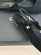 Chanel ladies black slingback flats close-up of gold CC charm on textured fabric