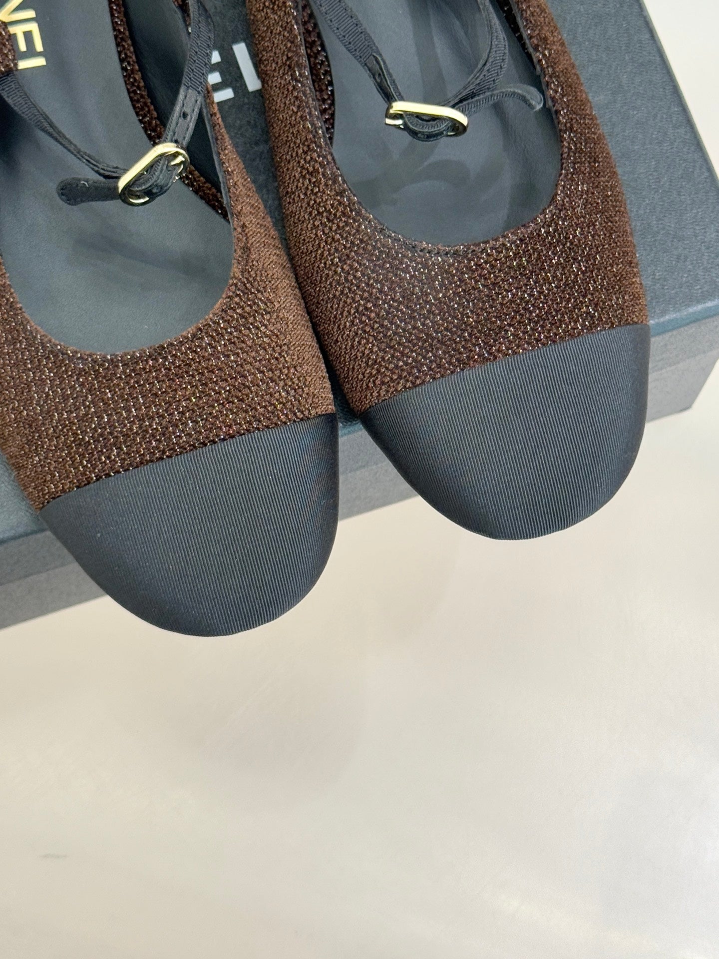 Chanel flats close-up, brown textured uppers with navy soles and gold metal detail