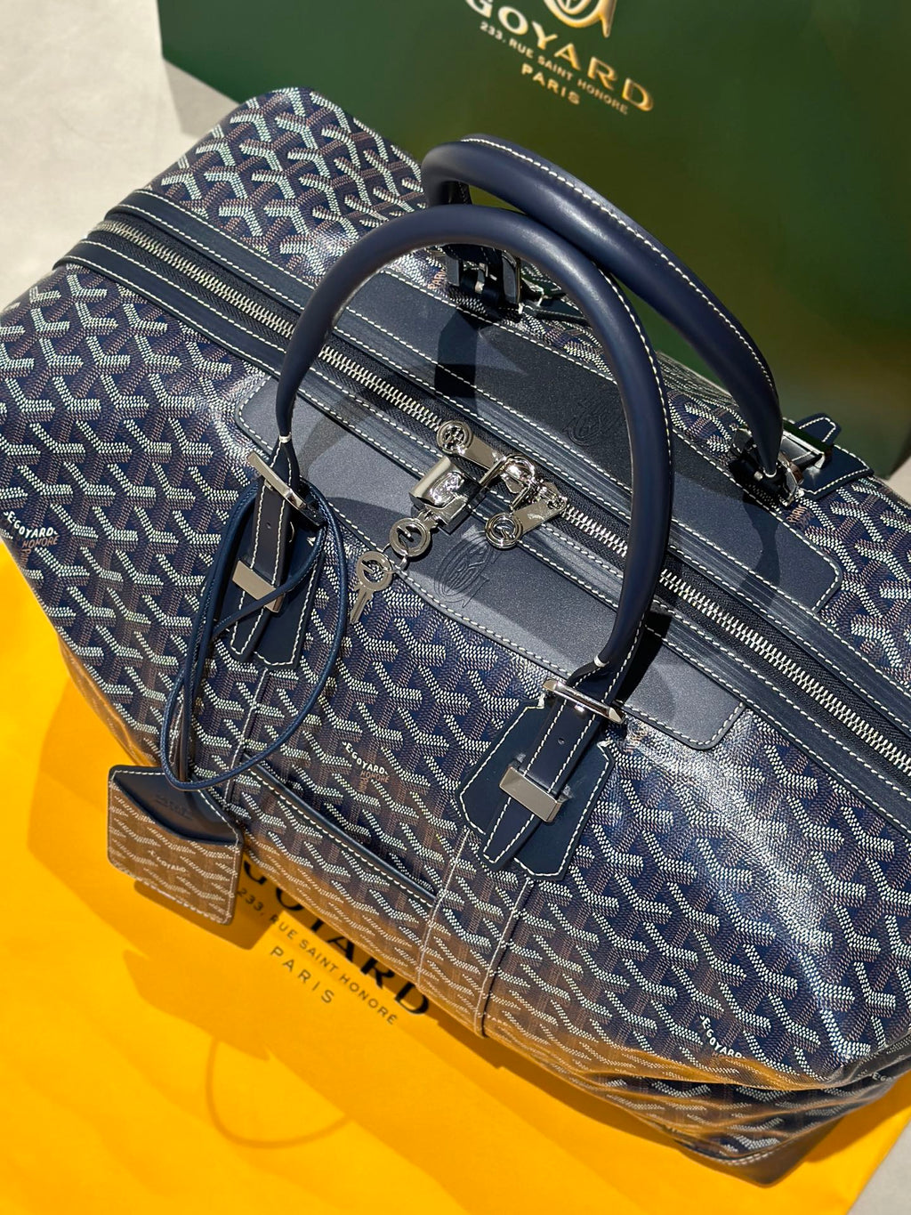 Goyard duffel bag with top handles and shoulder strap, dark blue monogram canvas.