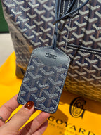 Goyard duffel bag leather side label on dark blue monogram canvas.