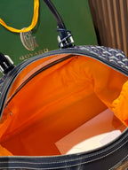 Goyard duffel bag open top, showing bright orange lining and leather edge trim.