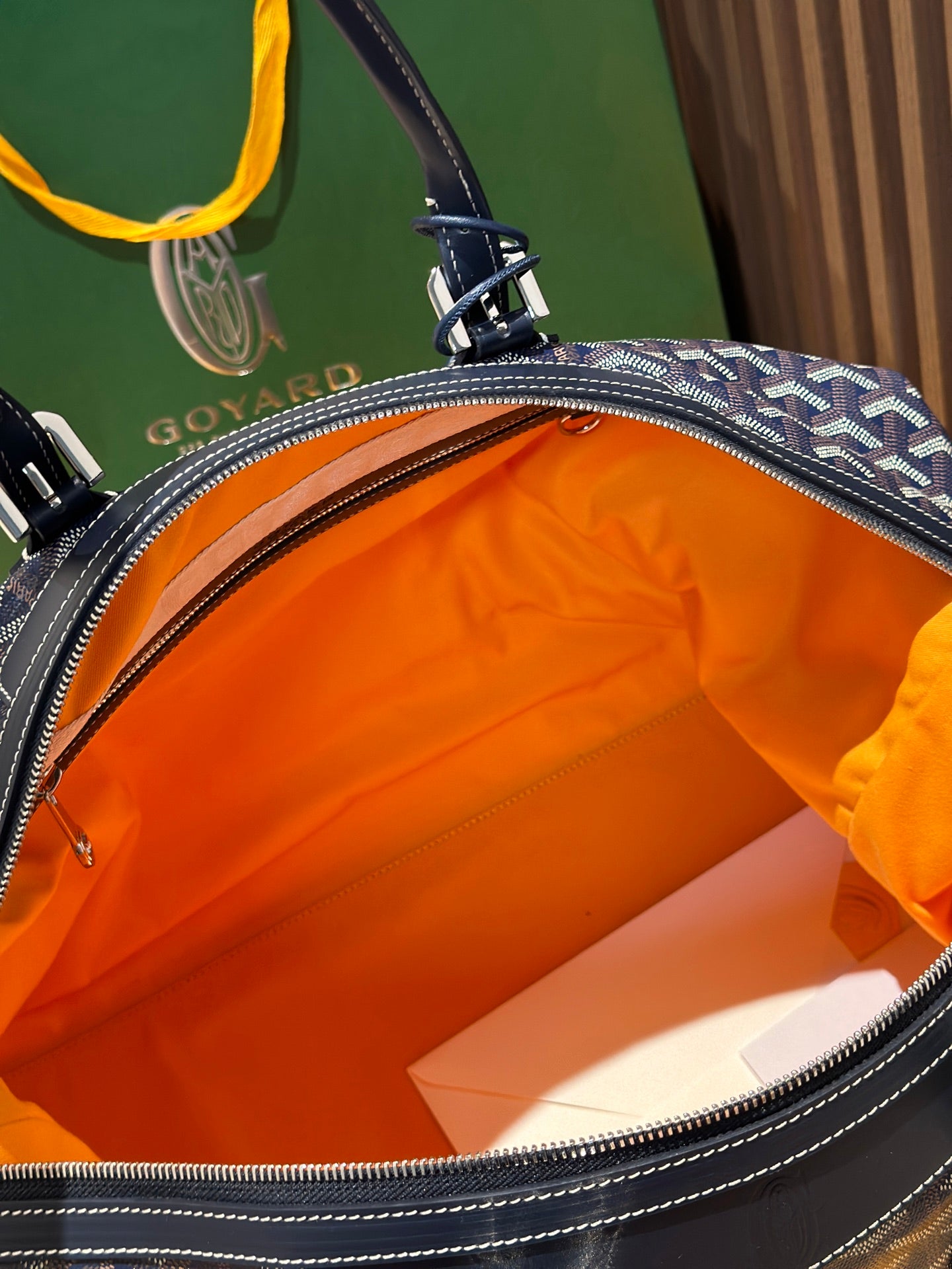 Goyard duffel bag open top, showing bright orange lining and leather edge trim.