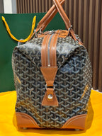 Goyard bag front view with tan leather strap, corner patches, and zip-top closure