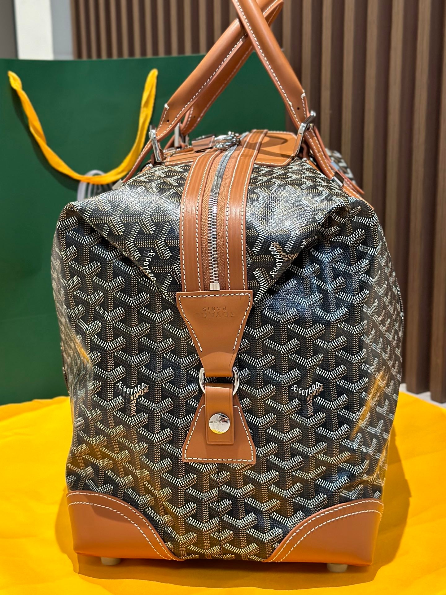 Goyard bag front view with tan leather strap, corner patches, and zip-top closure