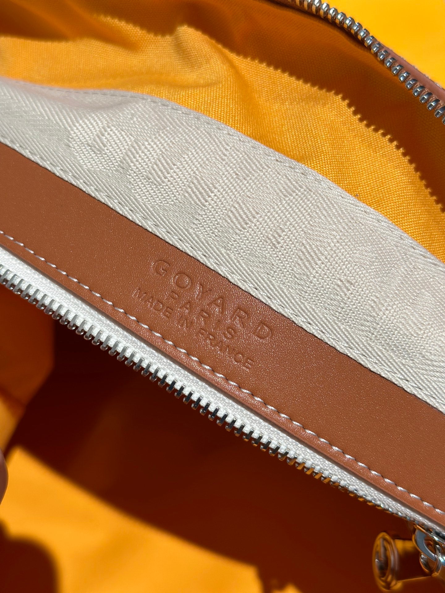 Goyard bag leather trim with stamped logo along the zipper seam
