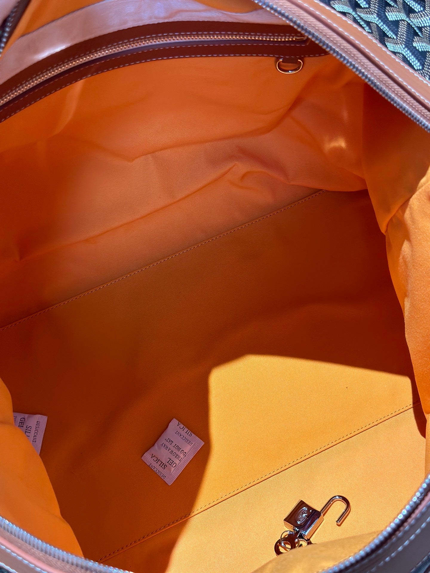 Goyard bag interior with orange lining and zippered compartment, leather-trim edges