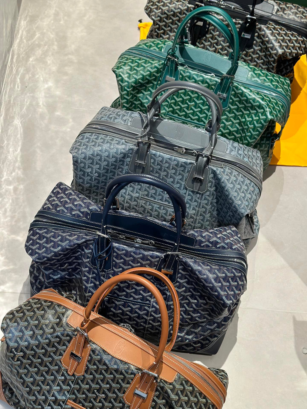 Set of Goyard patterned bags in stacked view, featuring green and navy tones