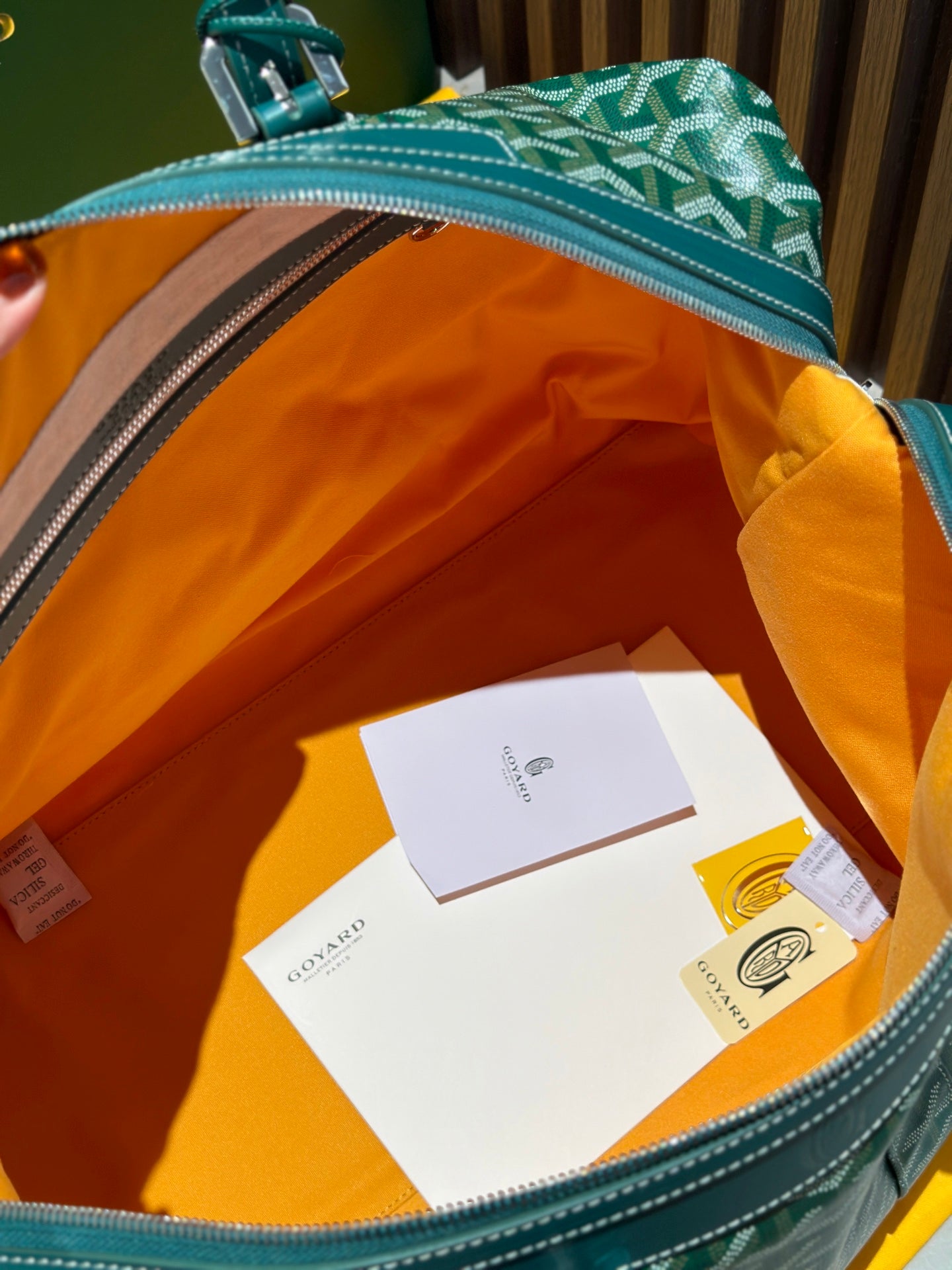 Open green duffel bag interior with orange lining and hanging tag