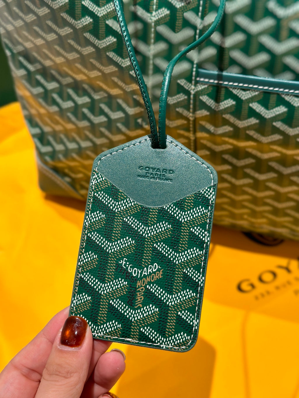 Green patterned bag tag with Goyard logo, attached to a strap