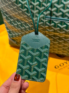 Green patterned bag tag with Goyard logo, attached to a strap