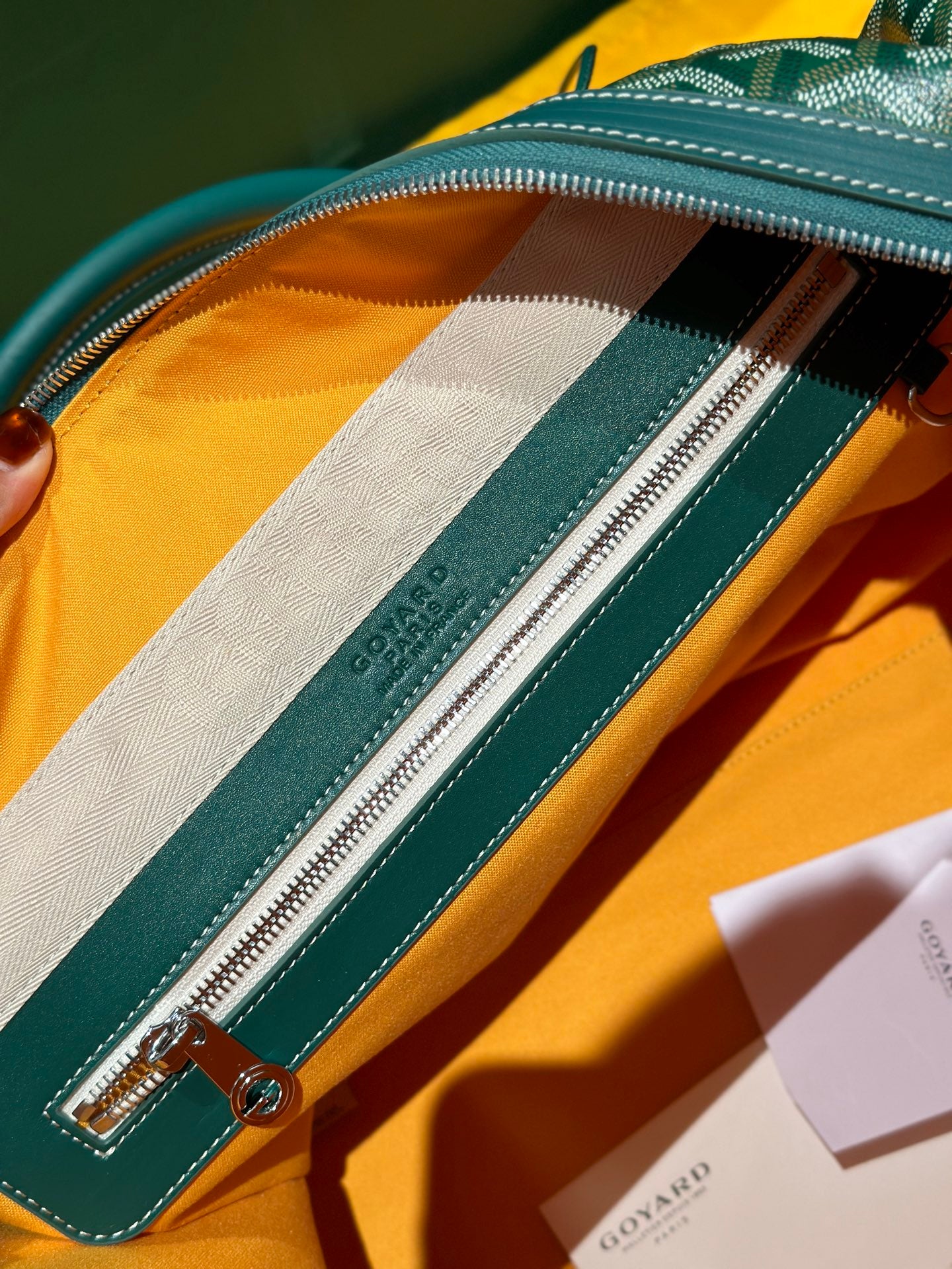 Close-up of green duffel bag interior zipper and stitched side logo stripe