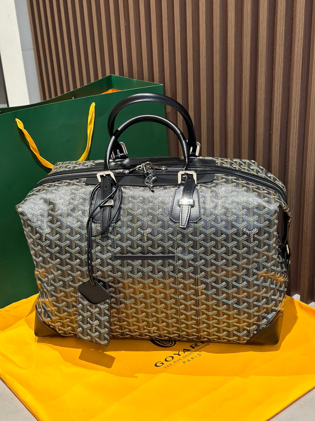 Goyard patterned travel bag with top handles and black trim, front zip pocket