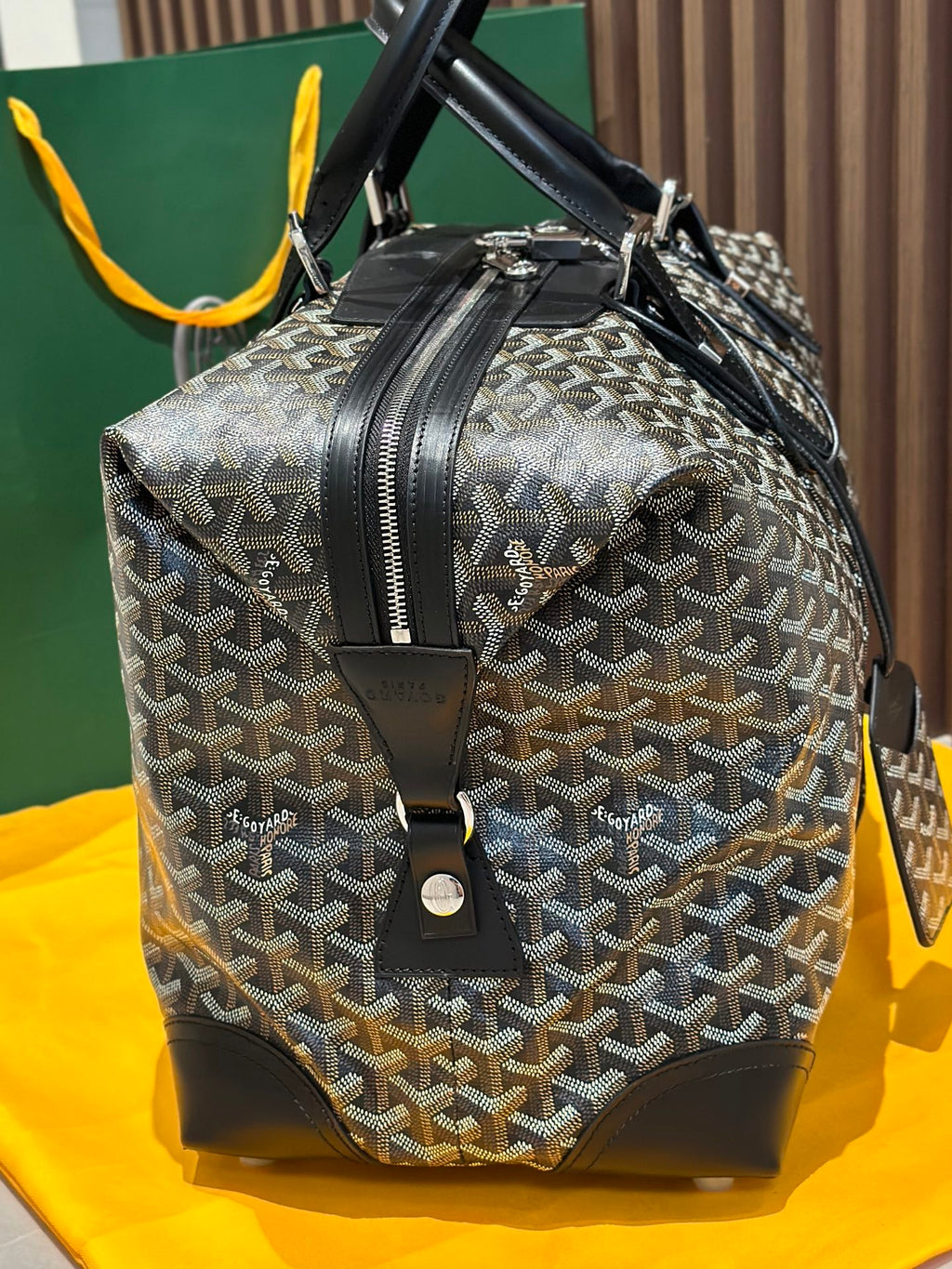 Goyard patterned duffel bag with black handles and front leather logo patch