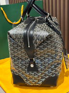 Goyard patterned duffel bag with black handles and front leather logo patch