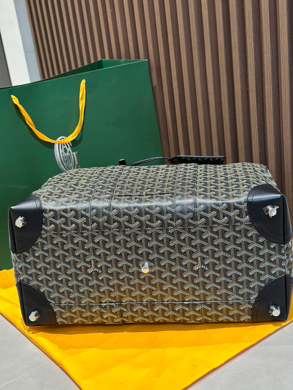 Goyard patterned top handle bag with black corner feet and front button hardware