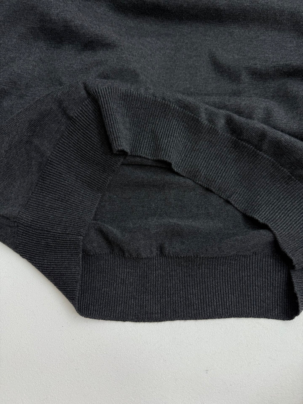 Dark gray ribbed sweater hem and sleeve cuff, knit texture visible