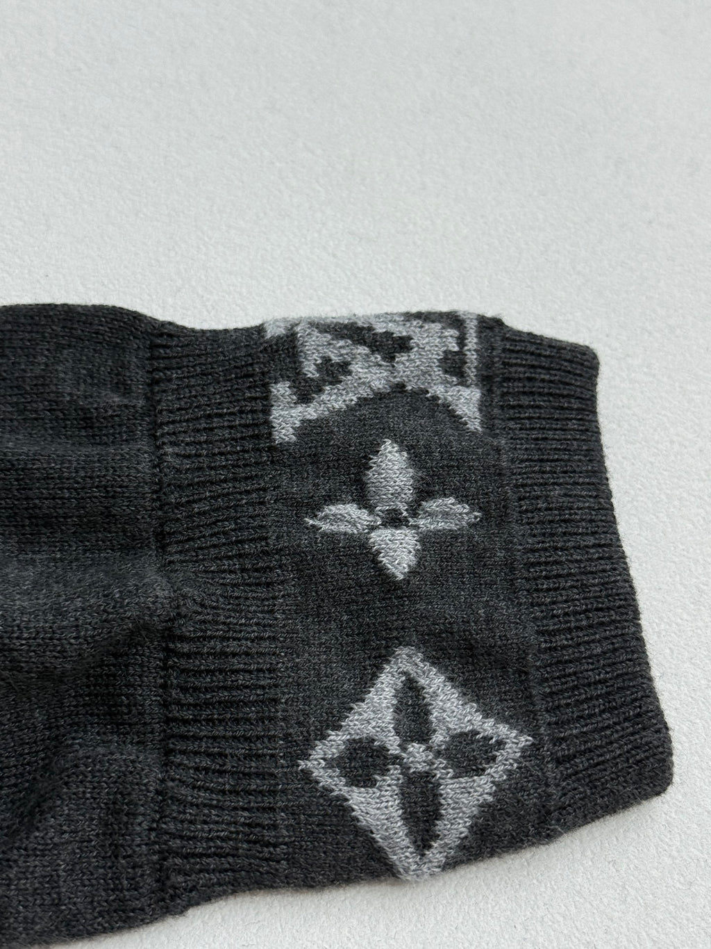 Dark gray sweater cuff with large monogram pattern and ribbed edge
