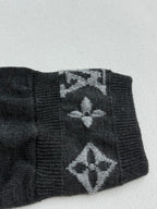 Dark gray sweater cuff with large monogram pattern and ribbed edge