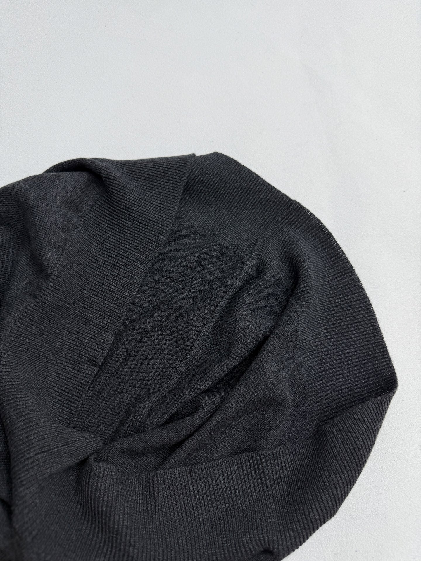 Dark gray sweater sleeve and shoulder seam with textured knit pattern